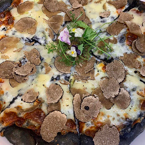 Schwarze Pizza mit frisch gehobeltem Trüffel